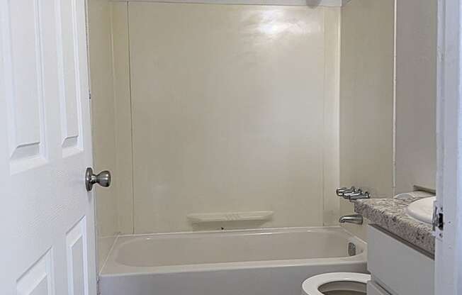 A bathroom with a toilet, sink, and bathtub at Waverly Park Apartments, Lansing
