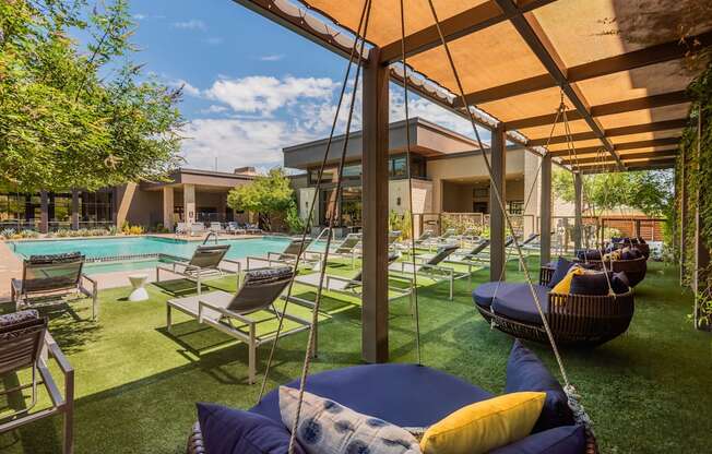 A patio with a pool and lounge chairs.