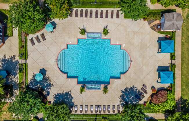 an aerial view of a swimming pool in the center of a city with trees