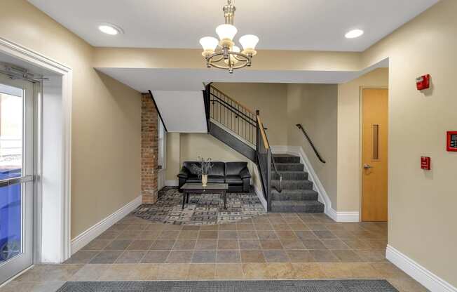a lobby with a staircase and a couch and a chandelier at The Granite Works Apartments , New York 14202