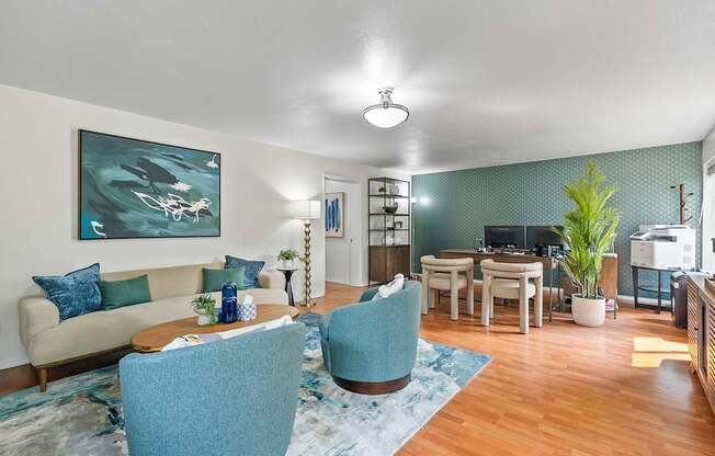 A living room with a blue chair and a painting on the wall.