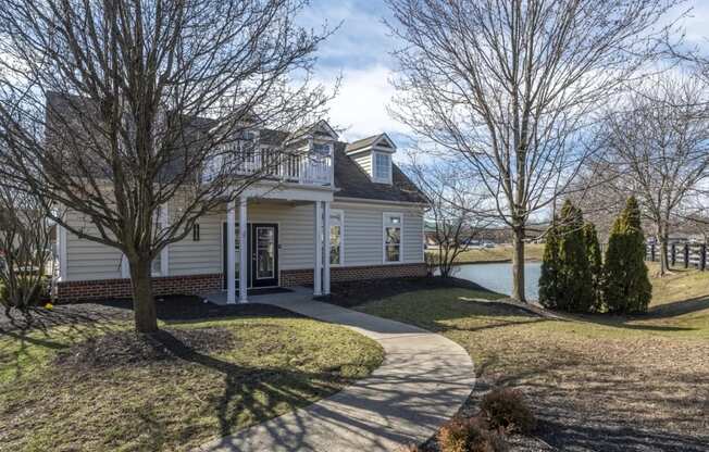 a white house with a driveway and a lake in the background at Traditions at Slate Ridge, Reynoldsburg, OH 43068