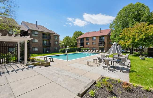 A pool area with a table and chairs and a building in the background.