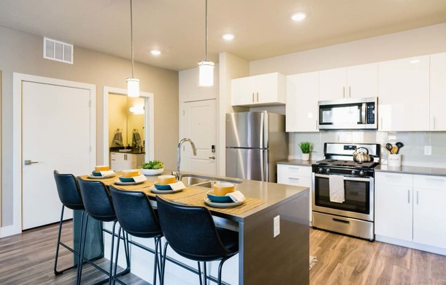 an open kitchen with a large island with blue chairs