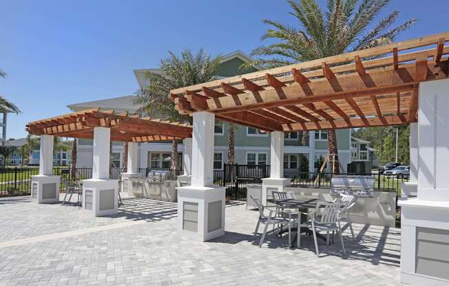 A patio with a table and chairs under a wooden pergola.