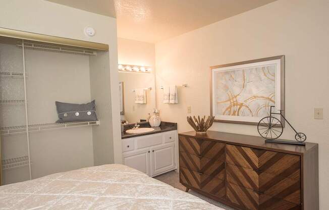 A bedroom with a bed, vanity, and a painting on the wall at Zinfandel Village Apartments, California, 95670