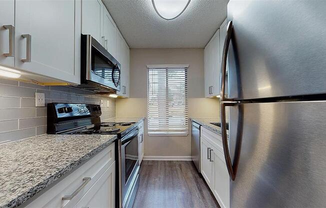 A kitchen with a stove top oven and a microwave above it. at Vue on Medlock, Peachtree Corners, Georgia