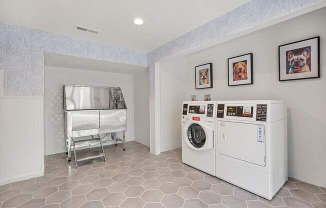 a laundry room with a washer and dryer and a bed in the corner