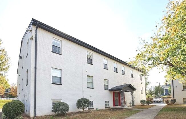 a white brick building with a red door at Viceroy Apartments, Durham , NC 27707