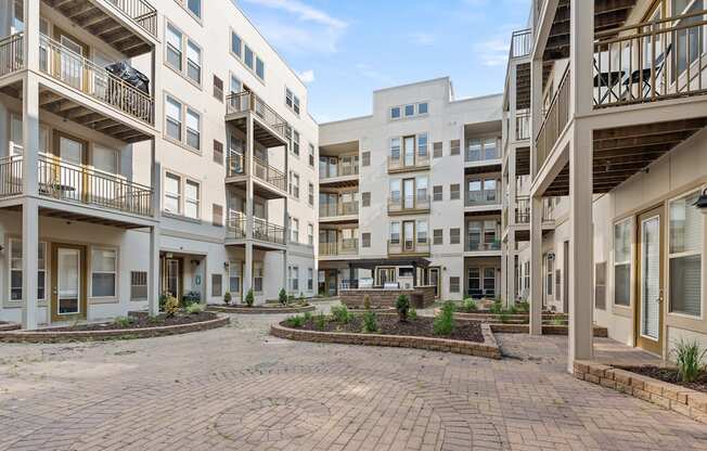 A courtyard surrounded by apartment buildings with a clear blue sky.