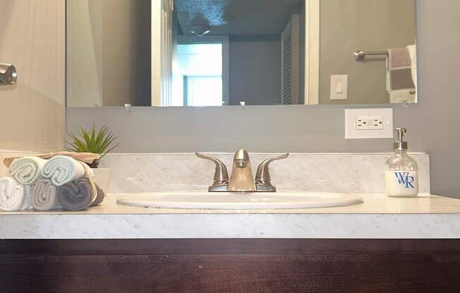 A bathroom sink with a marble countertop and a mirror above it.