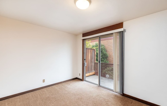 a living room with white walls and a sliding glass door to a patio