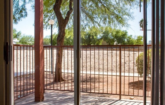 Private Patio with Sliding Glass Doors and Metal Railing Next to Tree