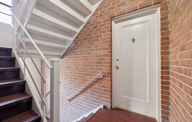 A white door is at the end of a brick wall hallway.