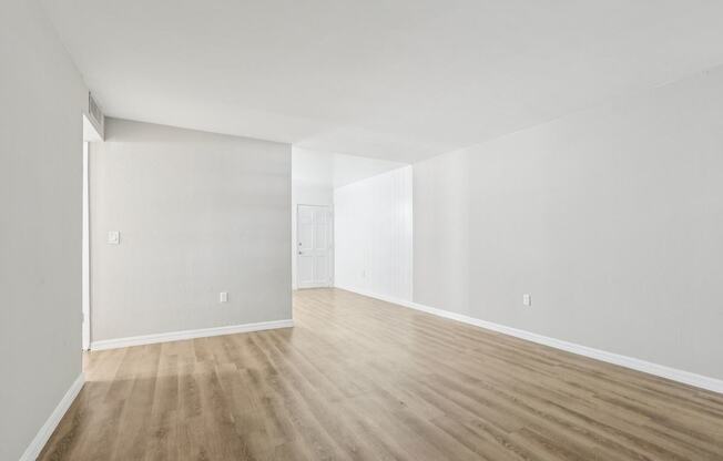 A room with wooden flooring and white walls.