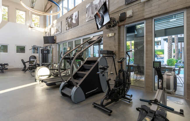 A gym with a variety of exercise equipment including treadmills, stationary bikes, and weight machines.