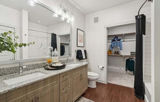 A bathroom with a wooden vanity and a mirror above it.