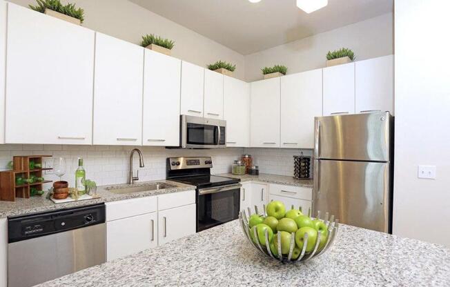 a kitchen with white cabinets and a bowl of fruit