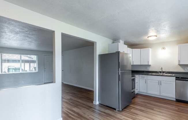 an empty kitchen with stainless steel appliances and white cabinets