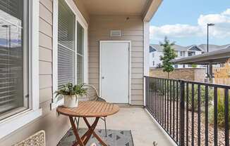 A small balcony with a table and chairs. at Connect at First Creek Apartments, Denver