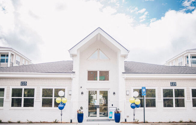 the front of a white building with balloons outside of it