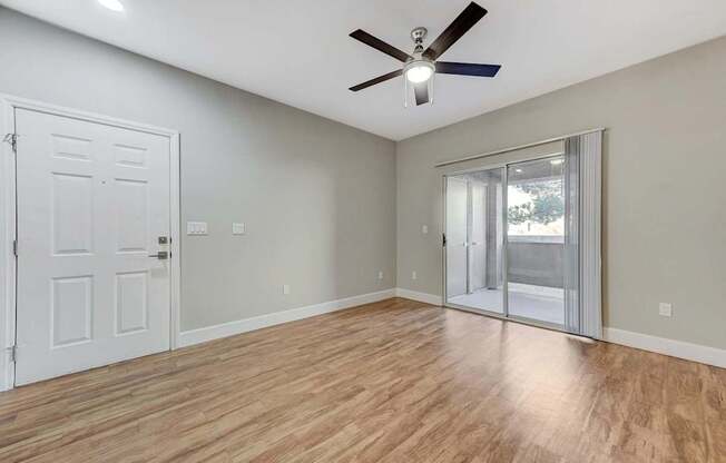 A room with a ceiling fan and wooden flooring.