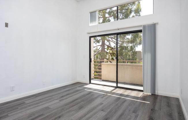 an empty living room with a sliding glass door to a balcony