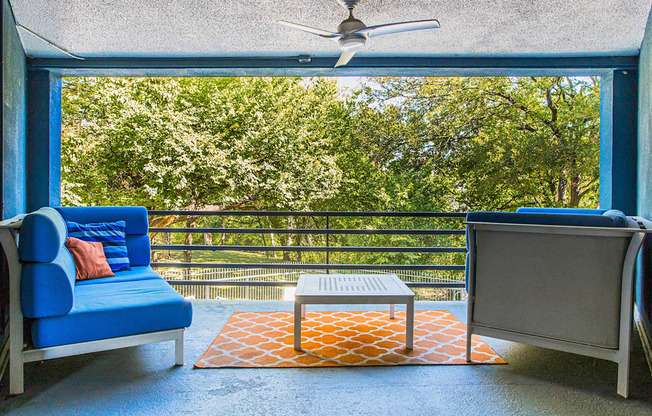 a balcony with a blue couch and a table and a ceiling fan