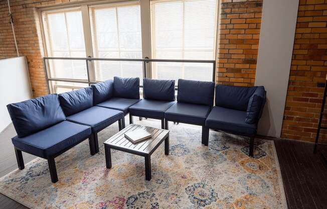 A blue sofa with a wooden coffee table in front of a brick wall.