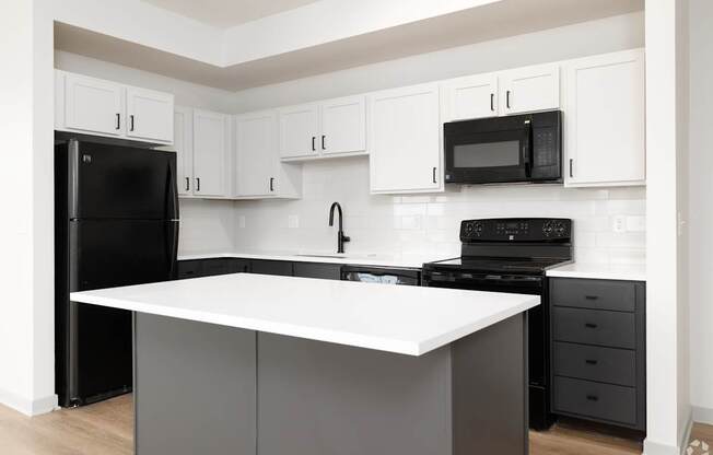 A kitchen with black appliances and white cabinets.