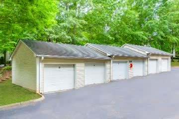 A row of garages with white doors and a red fire extinguisher on the wall.