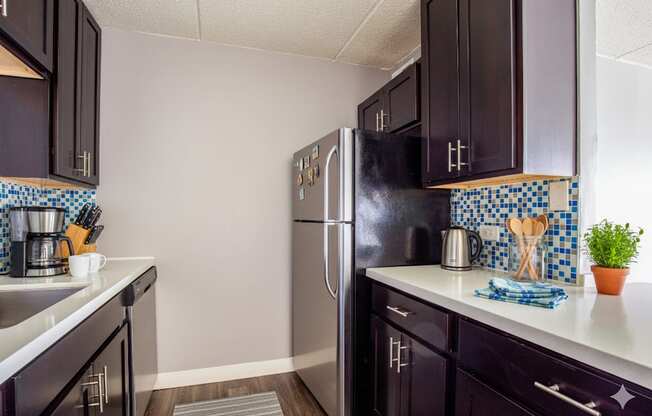 A kitchen with black cabinets and a black fridge.