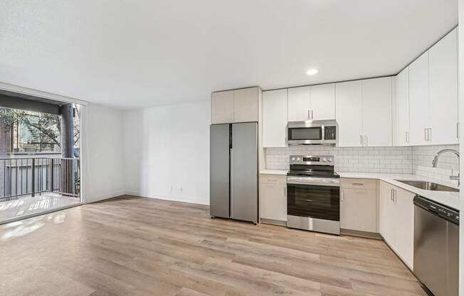 A kitchen with a refrigerator, oven, microwave, and sink.