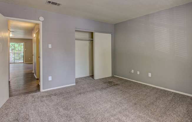 an empty living room with carpet and a door to a hallway