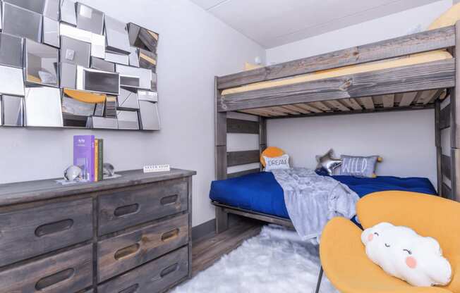 A room with a bunk bed, a dresser, and a wall art.