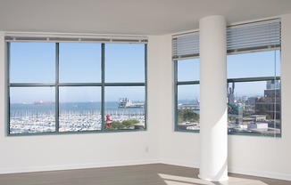 A white column stands in a room with two windows overlooking a marina.