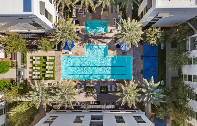 a birds eye view of a hotel with palm trees and a blue pool