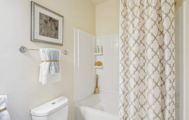 A white toilet sits next to a white bathtub in a bathroom.