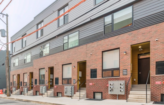 the side of a brick apartment building with stairs and a sidewalk