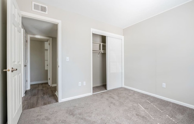 A room with a carpeted floor and two open doors.