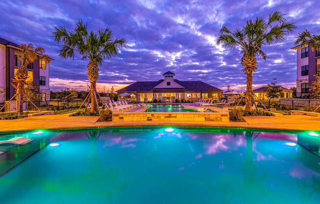 Swimming pool with palm trees and a building in the background at The Parker Austin, Pflugerville, Texas