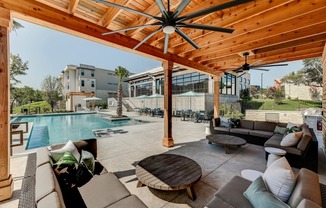 a backyard with a pool and a wooden deck with couches and tables