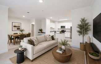 A living room with a white couch, a coffee table, and a dining table.