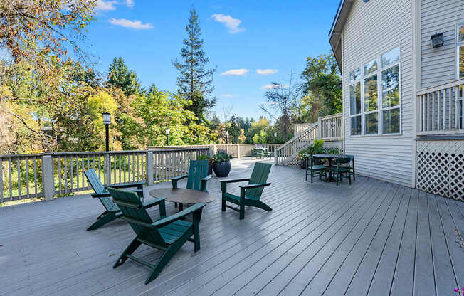 A wooden deck with green chairs and a table.