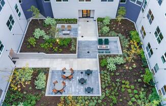 Unwind in the lushly landscaped courtyards at Modera Woodstock, where cozy lounge seating and a fire table create the perfect outdoor retreat in the heart of Portland.