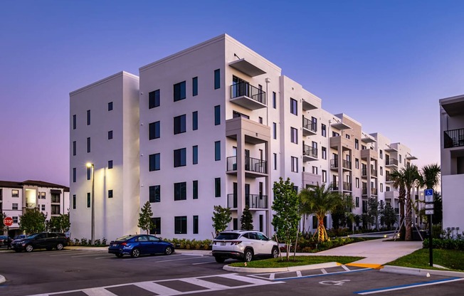A modern apartment building with cars parked in front.