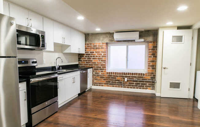 Kitchen with Stainless Steel Appliances and Living Area with Resurfaced Wood Floors