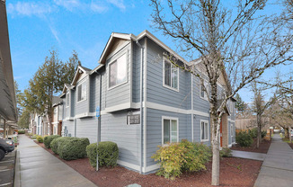A grey house with a tree in front of it.
