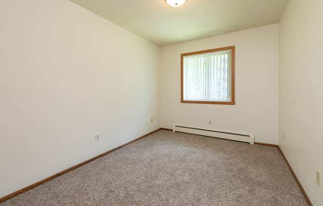 a bedroom with carpet and a window. Fargo, ND Islander Apartments