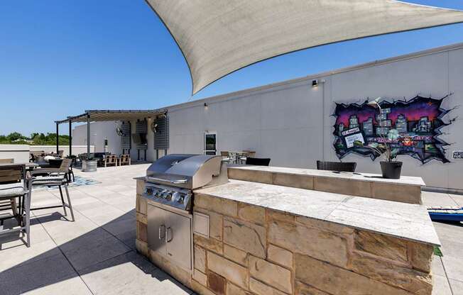 A barbecue grill is on a patio with a mural on the wall.